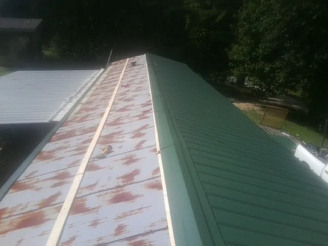 Old rusted panels beside newly installed green metal roofing — Wind Damage Roof Repair by Roofing Brothers in Northwood