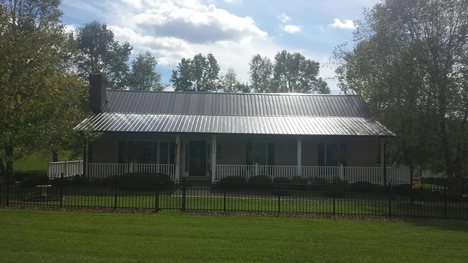 Gray metal roof on a brick ranch with a full width front porch — Gutter Guard Installation work by our crew in Northwood