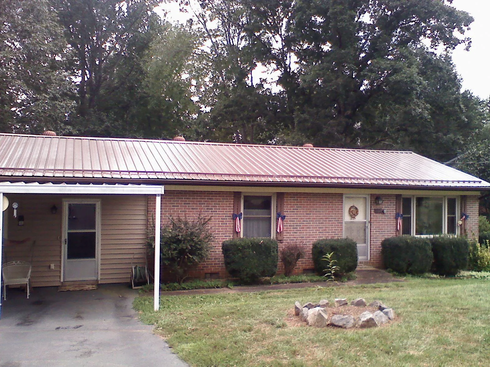 Bronze metal roof and carport on a brick ranch home — Roof Repair work by our crew in Northwood